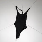 Maillot de bain une pièce noir haut de gamme, mis sous tension par des câbles pour souligner sa technicité.